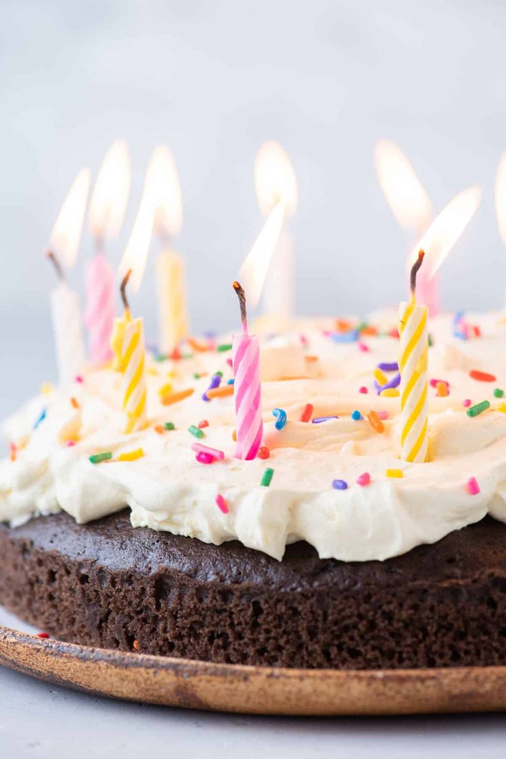 a chocolate cake with white frosting and multi - colored candles is shown on a plate