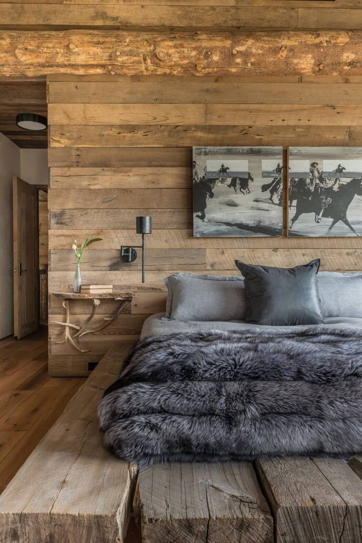 a bedroom with wood paneling and gray fur on the bed, along with two paintings