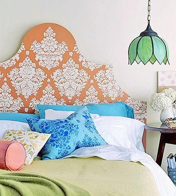 a bedroom with an orange headboard and colorful pillows on the bed, along with other accessories