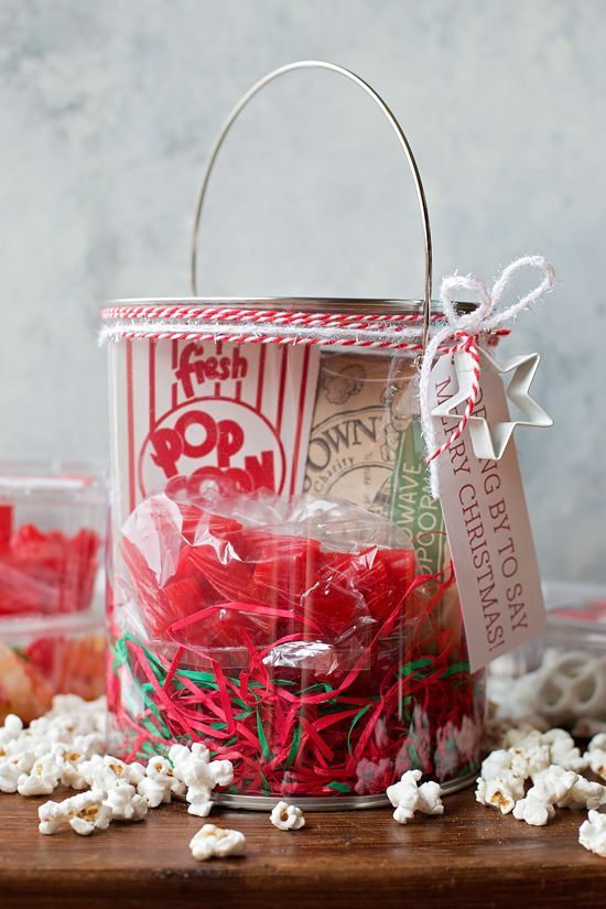 a bucket filled with red and white popcorn sitting on top of a wooden table next to other