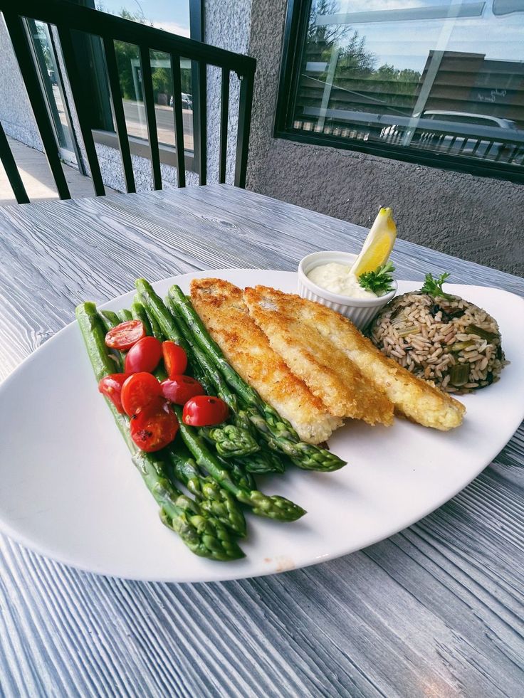 a white plate topped with fish and asparagus