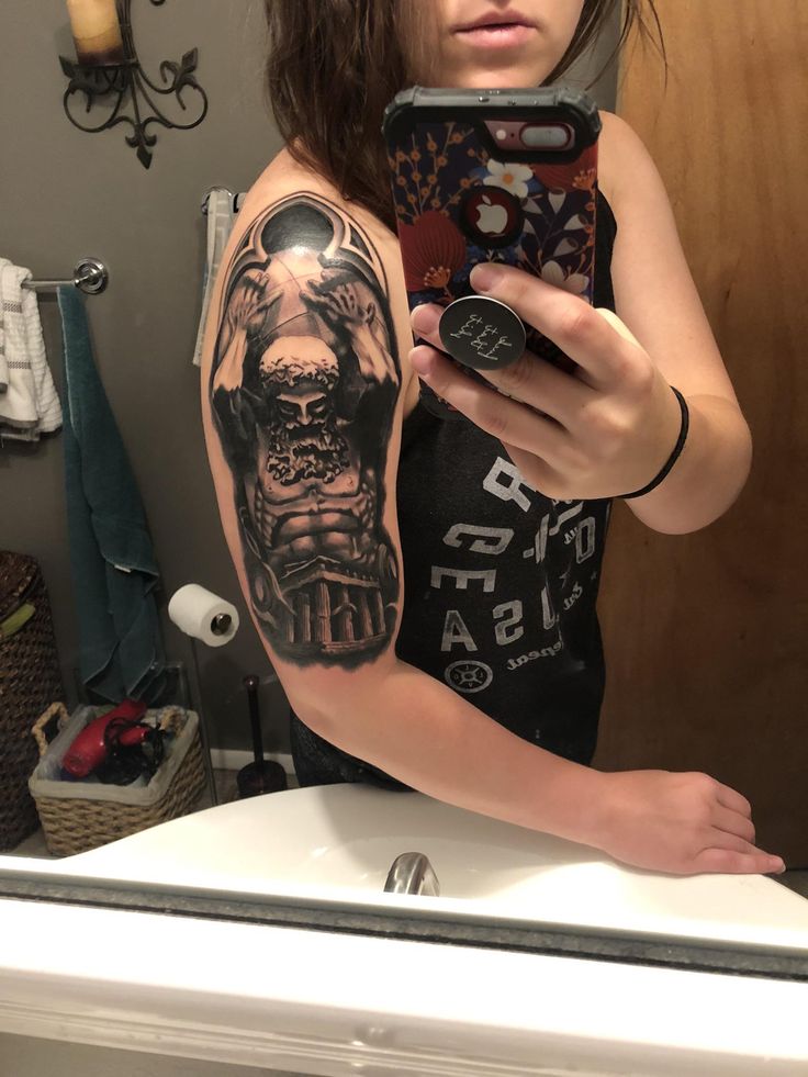 a woman taking a selfie in the mirror with her cell phone and tattoo on her arm