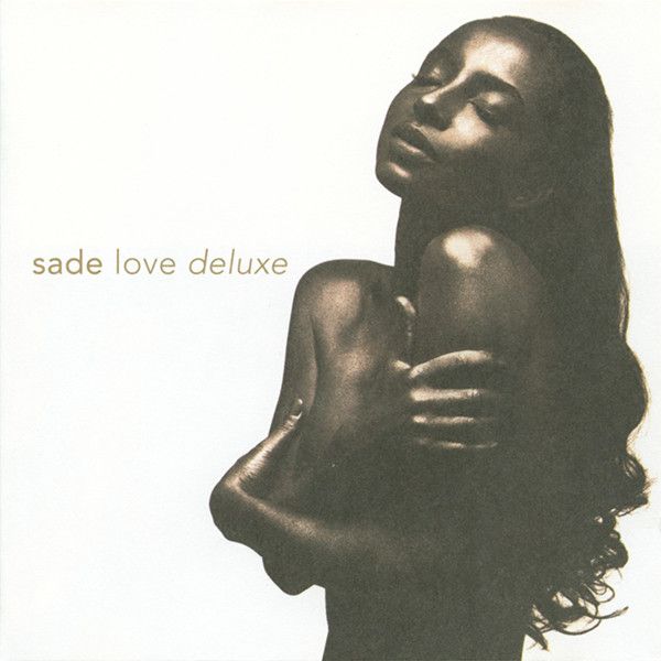 a woman with long hair holding a baby in her arms and the words sade love deluxe written on it