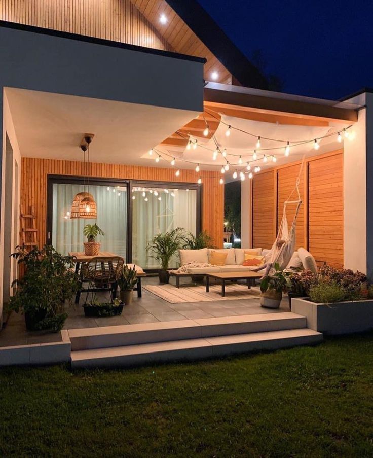 an outdoor patio with lights strung over it and furniture on the steps leading up to the deck