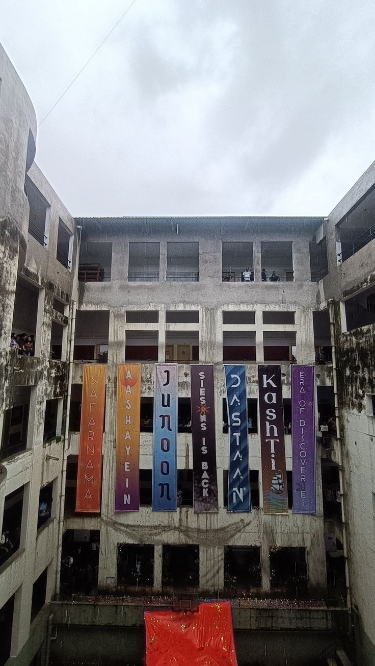 an abandoned building with colorful banners hanging from it's sides and windows on the side