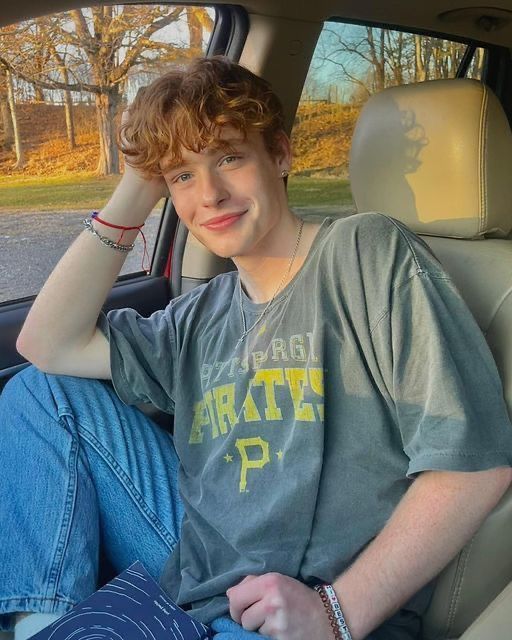 a young man sitting in the back seat of a car