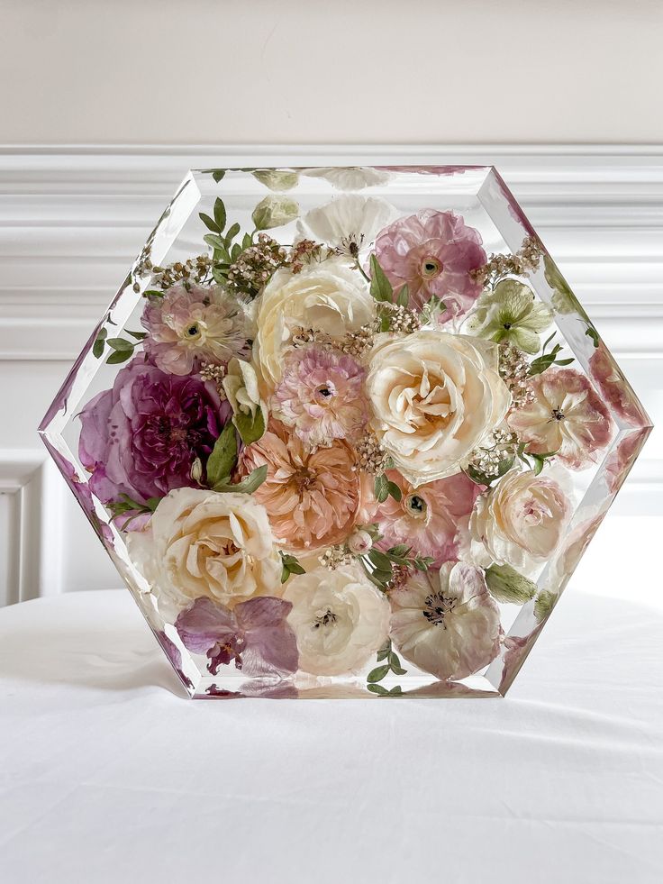 a glass vase filled with flowers on top of a bed