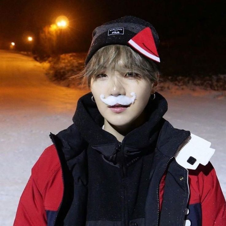 a young man standing in the snow with a fake moustache on his face