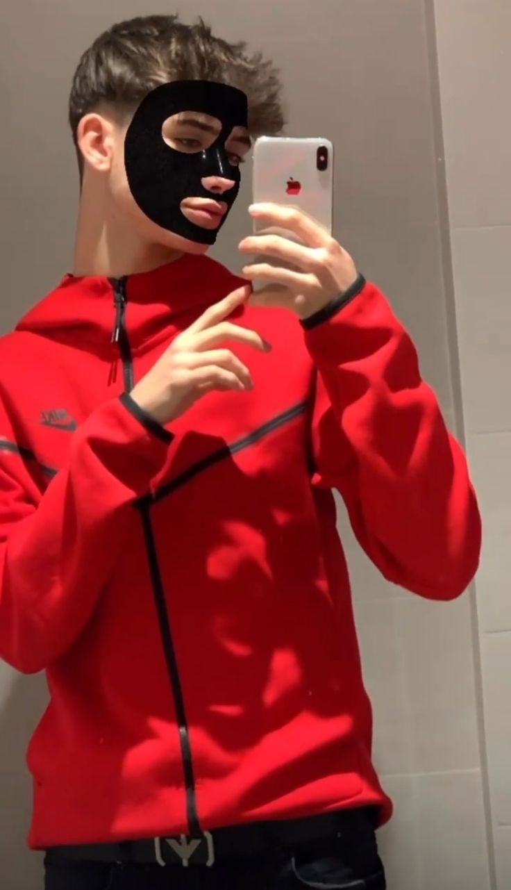 a man in a red hoodie is taking a selfie with his cell phone