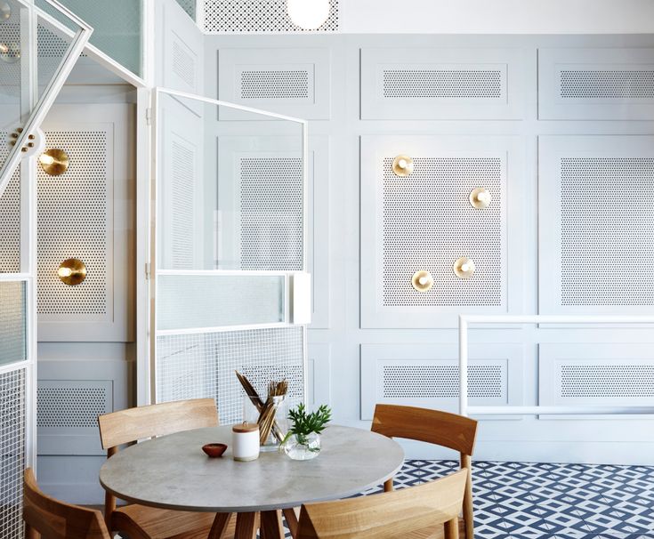 a table and chairs in a room with white paneling on the wall behind them