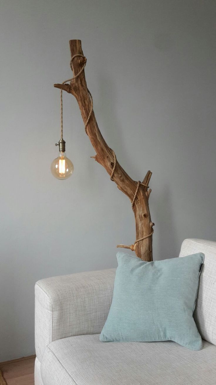 a white couch sitting next to a tree branch with a light bulb hanging from it