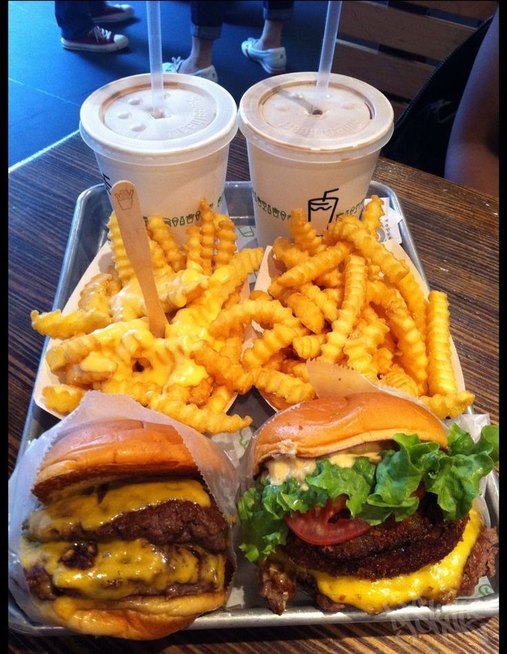 two burgers and fries on a tray with drinks