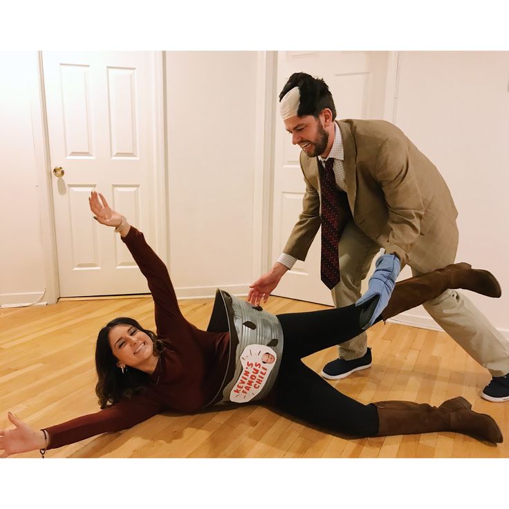 a woman laying on the floor next to a man in a suit with his arms out