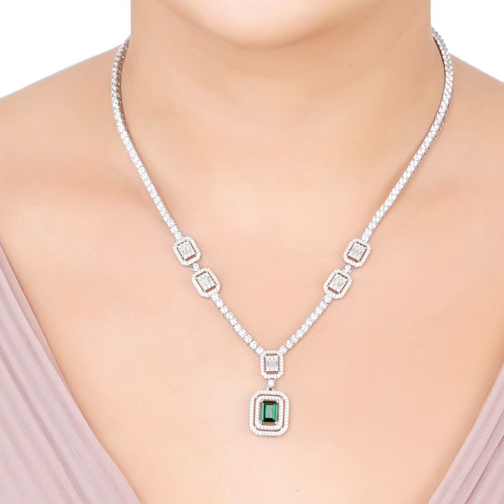 Elevate your elegance with the Evita Emerald Statement Necklace in Silver. This exquisite piece redefines luxury with its tennis necklace design. The centrepiece is a breath-taking pendant drop, featuring two distinct rectangular settings. The larger setting cradles a stunning lab-grown emerald, enveloped by two dazzling rows of zircons. This masterpiece gracefully connects to a smaller rectangular setting, where baguette-cut zircons are framed by a single row of glistening zircons.  Adding to i Elegant Gemstone Tennis Necklace For Anniversary, Elegant Emerald Necklace With Brilliant Cut, Elegant Cubic Zirconia Emerald Necklace, Emerald Statement Necklace, Silver Necklace Statement, August Birthstone Jewelry, July Birthstone Jewelry, Necklace Design, Zodiac Jewelry