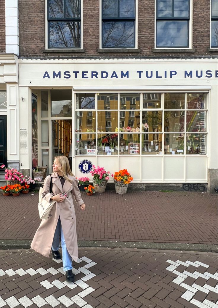 a woman walking down the street in front of a flower shop