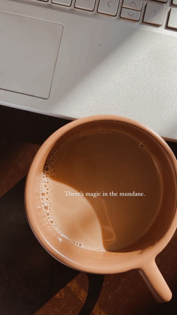 a coffee mug sitting on top of a desk next to a laptop computer and keyboard