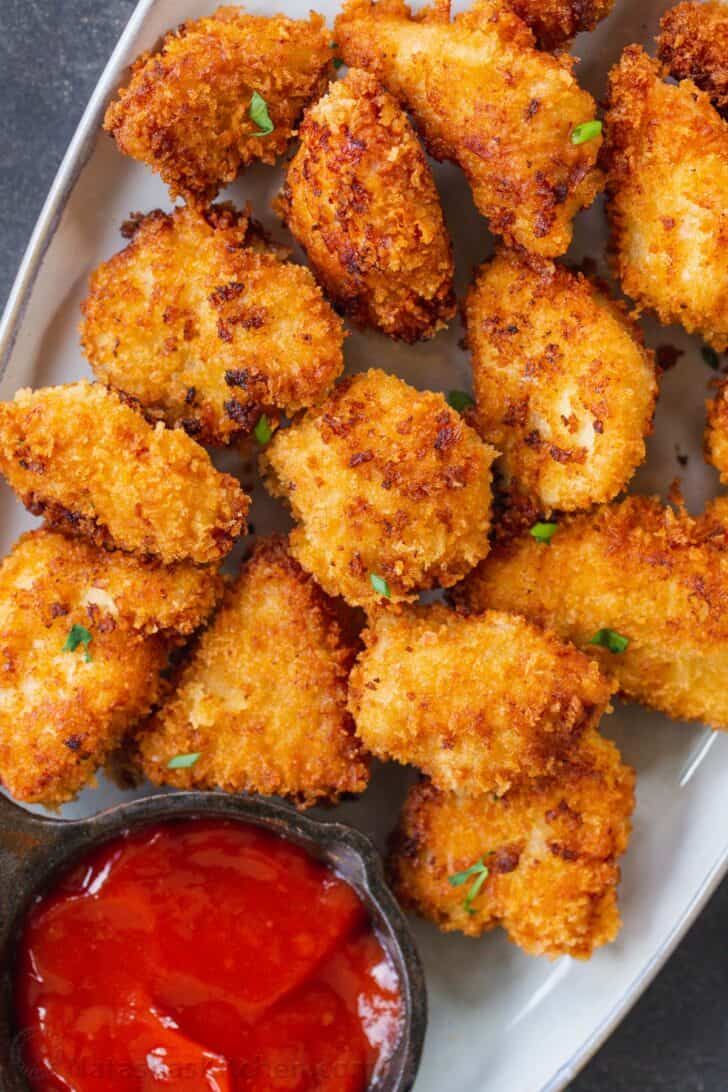 fried chicken nuggets with ketchup and dipping sauce on a white plate