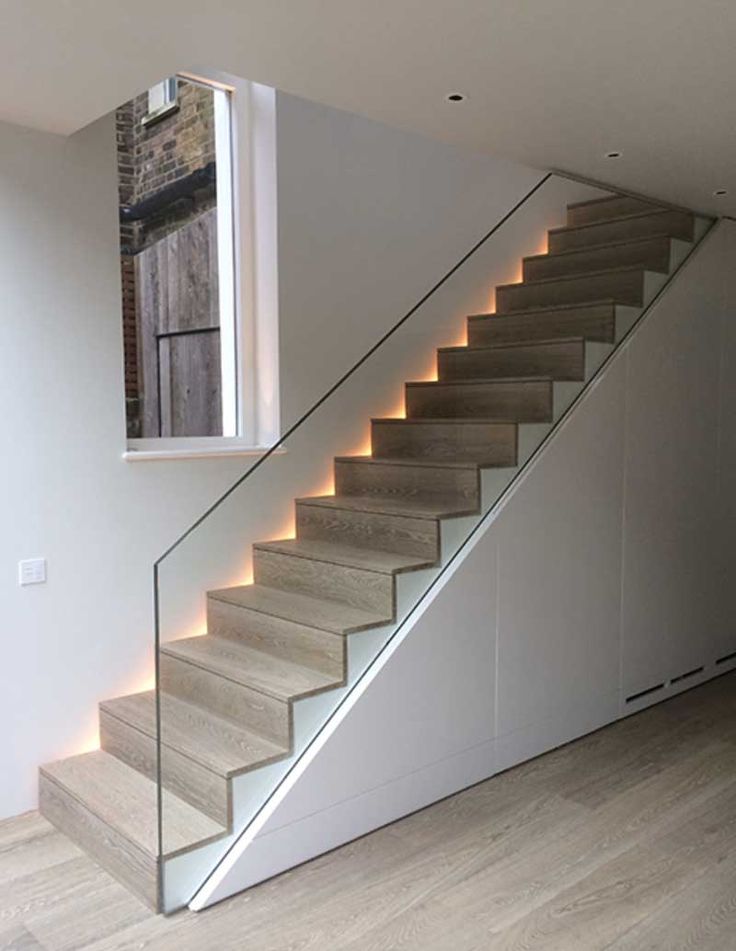 a stair case with lights on the bottom and sides in an empty room next to a window