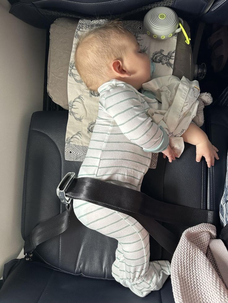 a baby sleeping in the back of a car seat