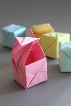 four origami boxes sitting next to each other on top of a gray surface