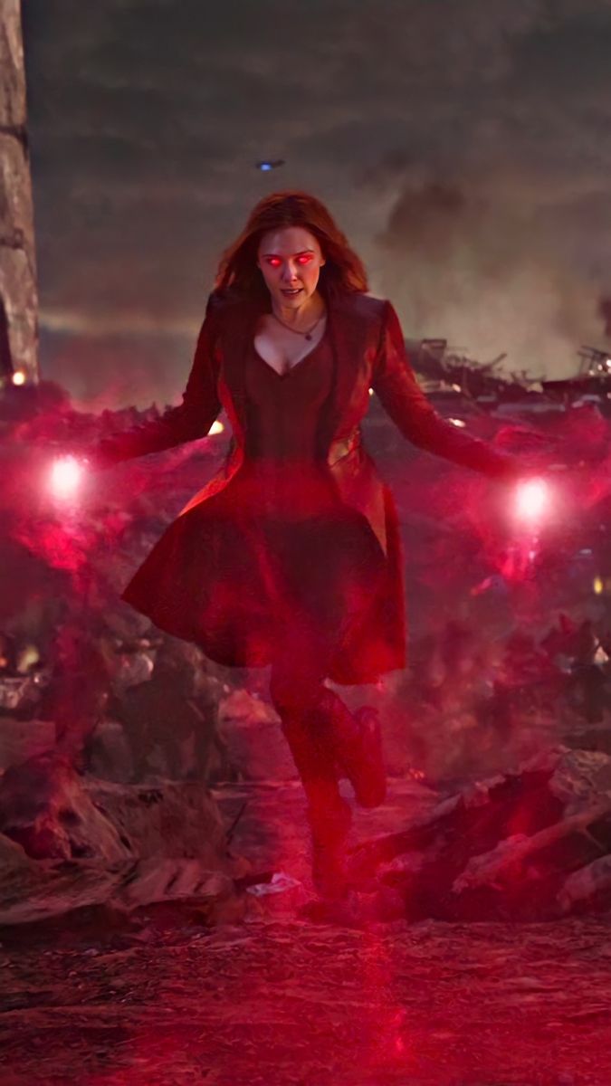 a woman in a red dress is walking through the dark with her arms spread out