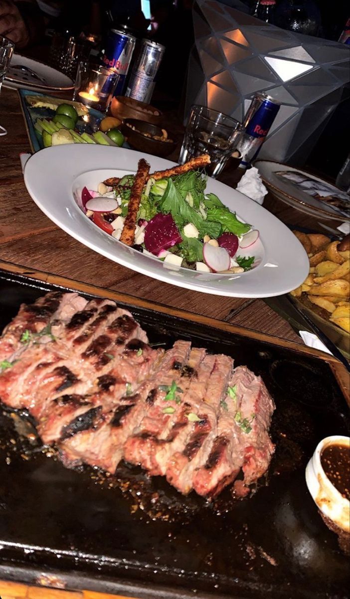 steaks and vegetables are being cooked on the grill at a restaurant in an upscale setting