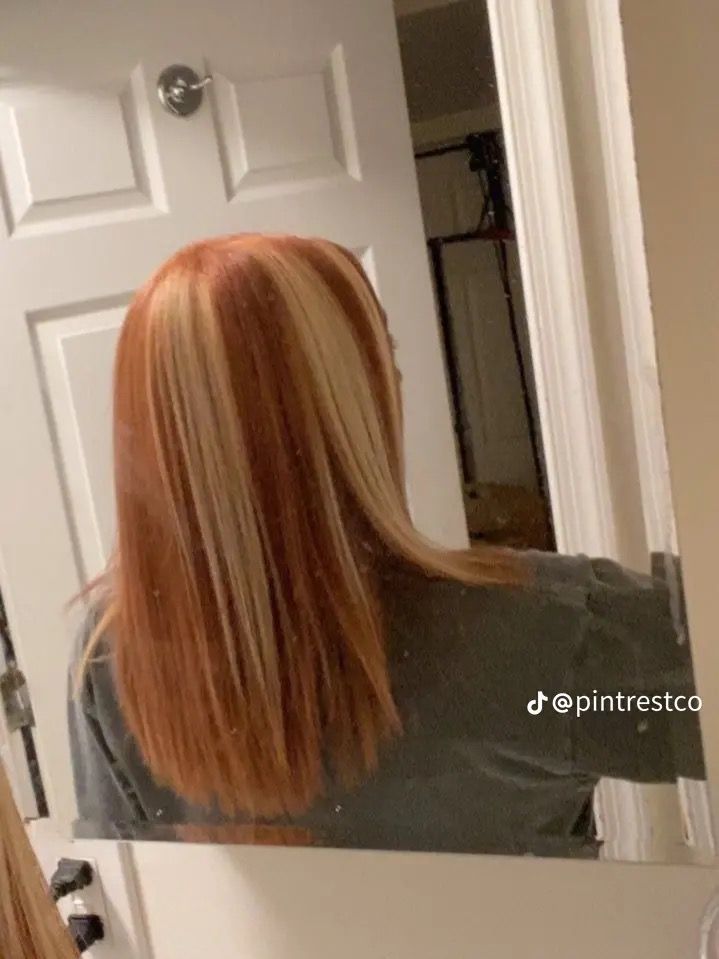 a woman with long red hair looking at herself in the mirror