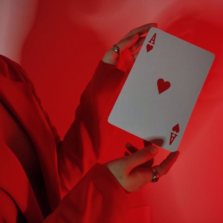 a woman holding up a playing card with hearts on the front and back of it