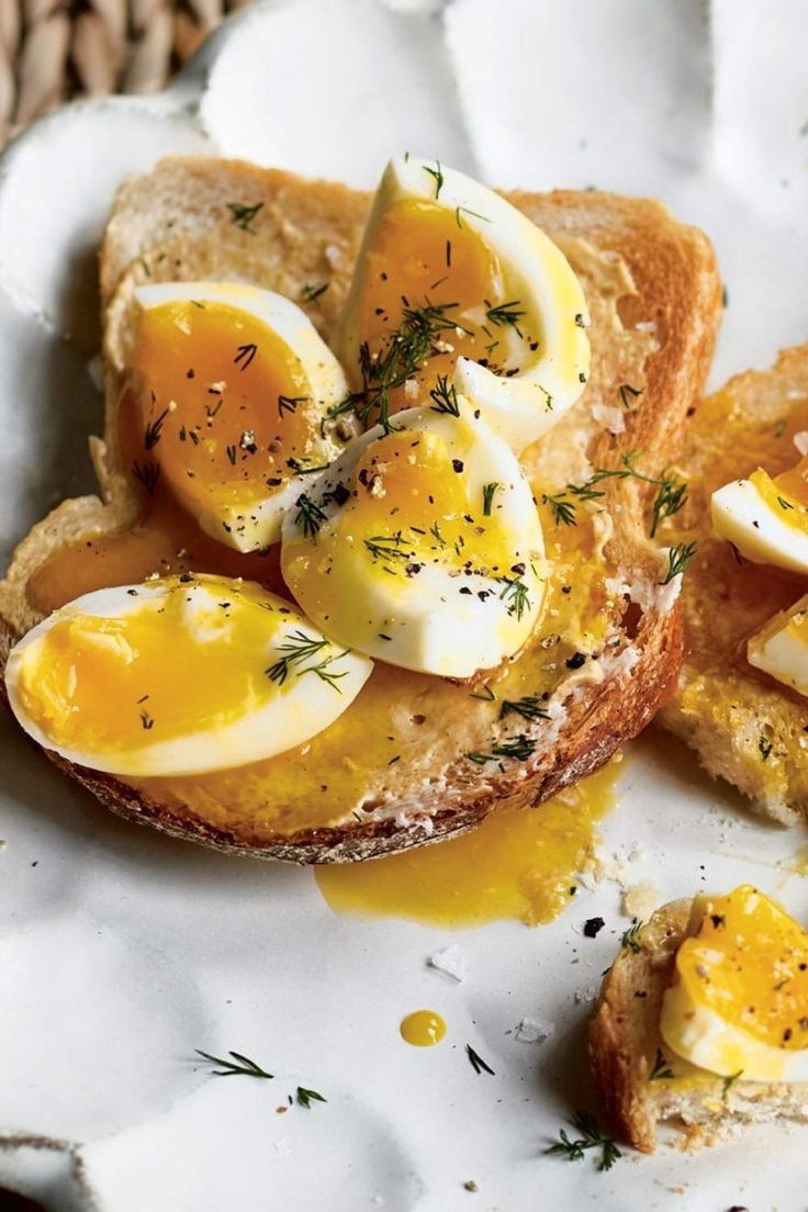 two pieces of bread with boiled eggs on them and herbs sprinkled on top