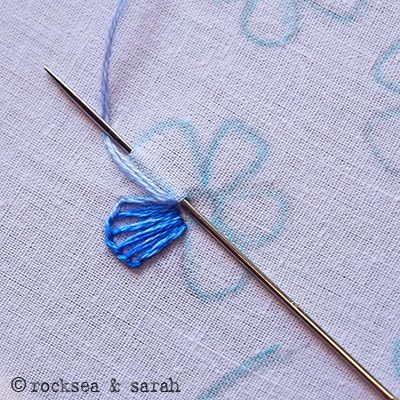 the needle has been hooked up to an embroidered piece of fabric with blue thread on it