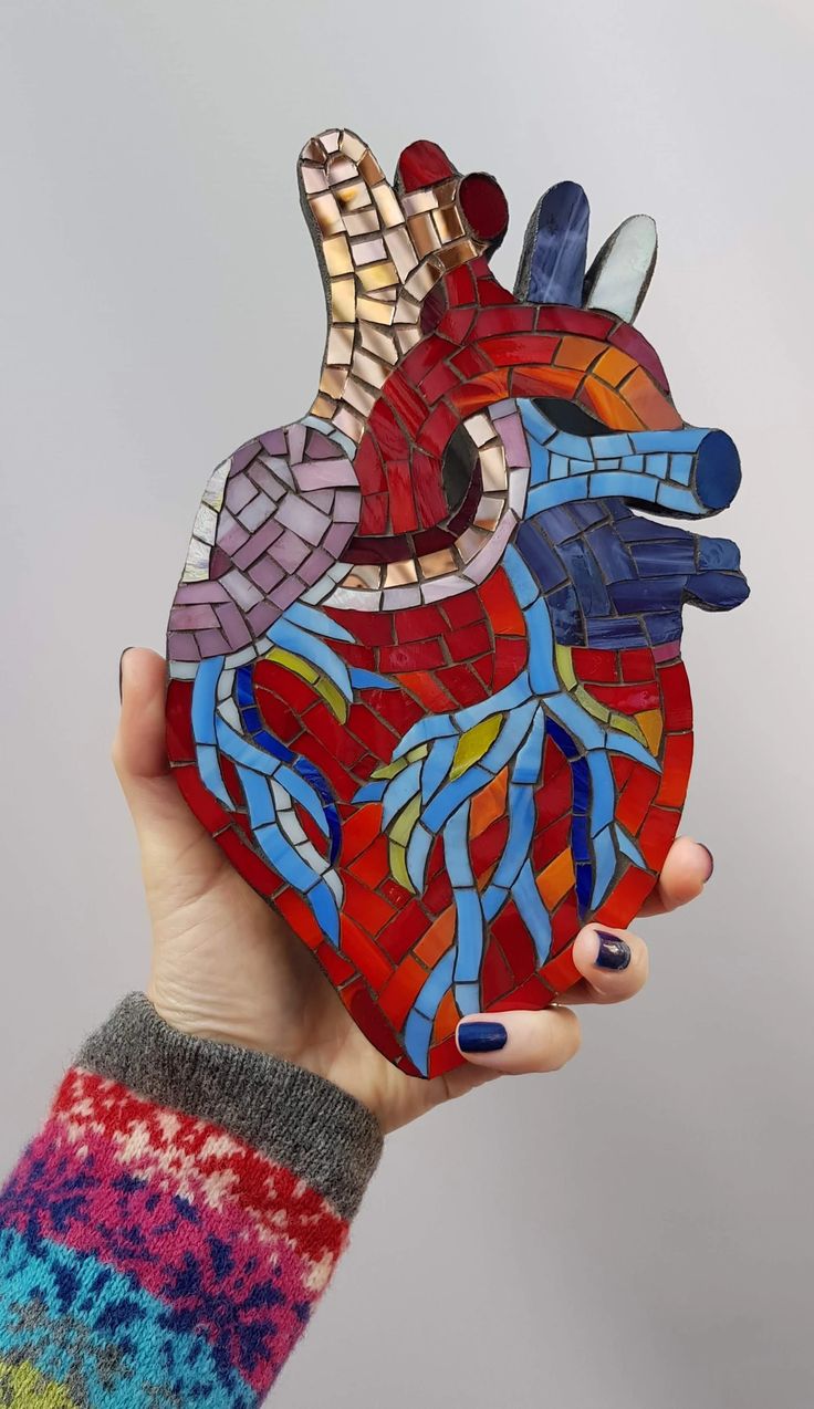 a hand holding up a stained glass heart