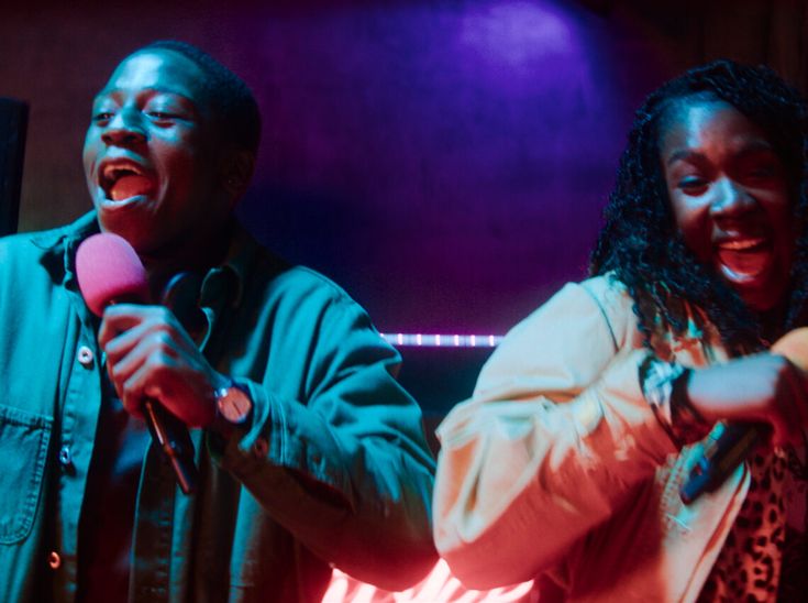 two people singing into microphones in a dark room