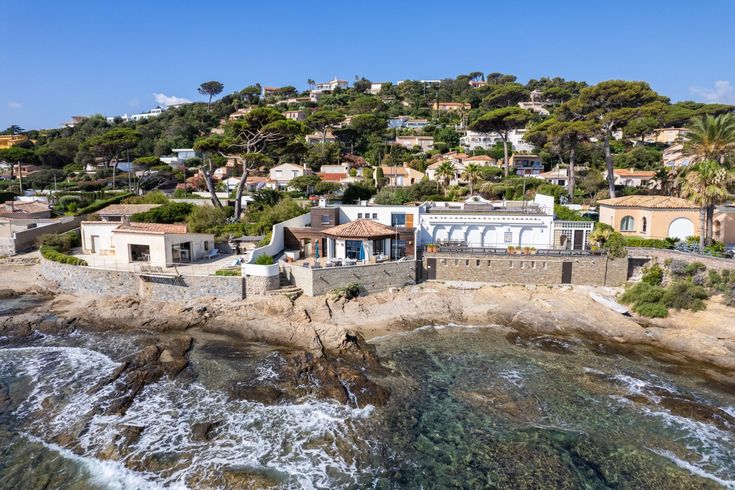 an aerial view of a house on the coast with waves crashing in front of it