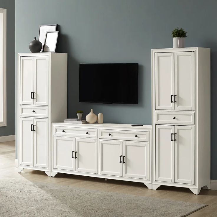 a living room with white furniture and a flat screen tv mounted on the side of it