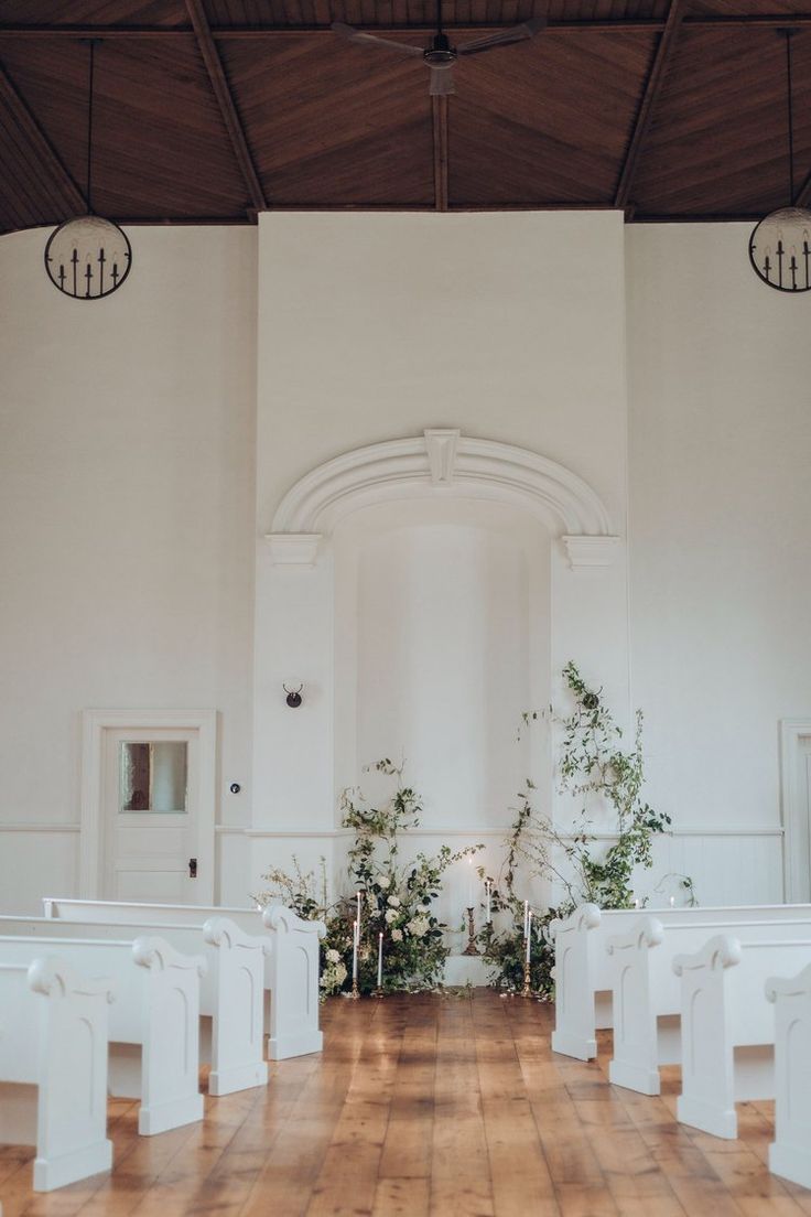 an empty church with white chairs and plants