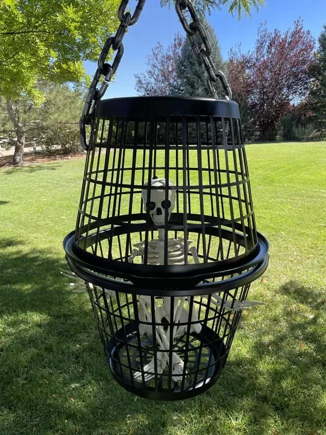 a skeleton in a cage hanging from a tree