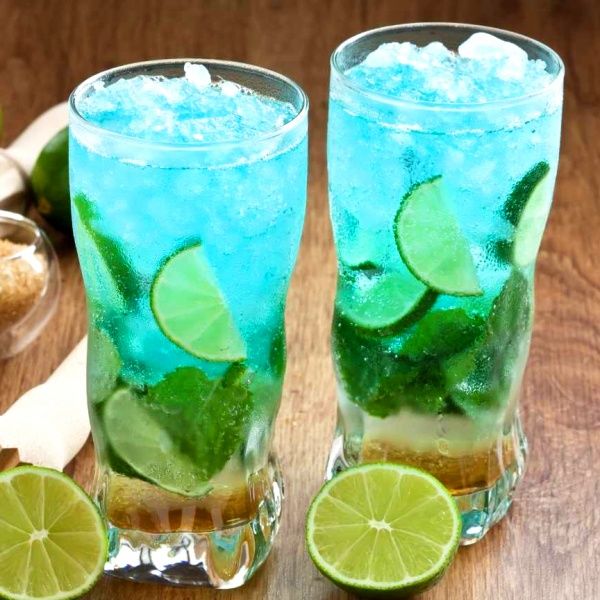 two tall glasses filled with ice and limes