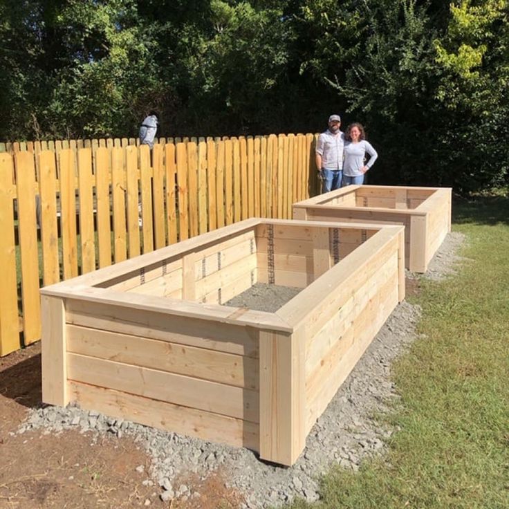 two people standing next to wooden raised beds