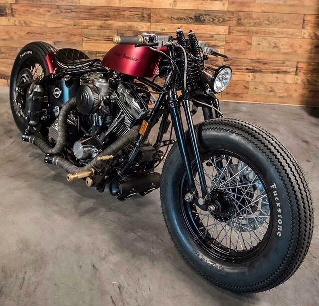 a red motorcycle parked in a garage next to a wooden wall with black rims