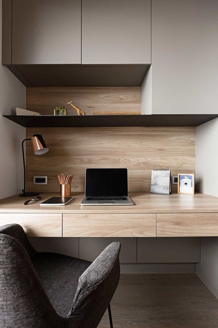 a laptop computer sitting on top of a wooden desk next to a gray chair and lamp