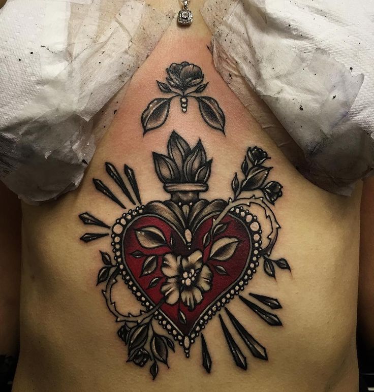 a woman's back with an intricate heart tattoo on her stomach and flowers in the center