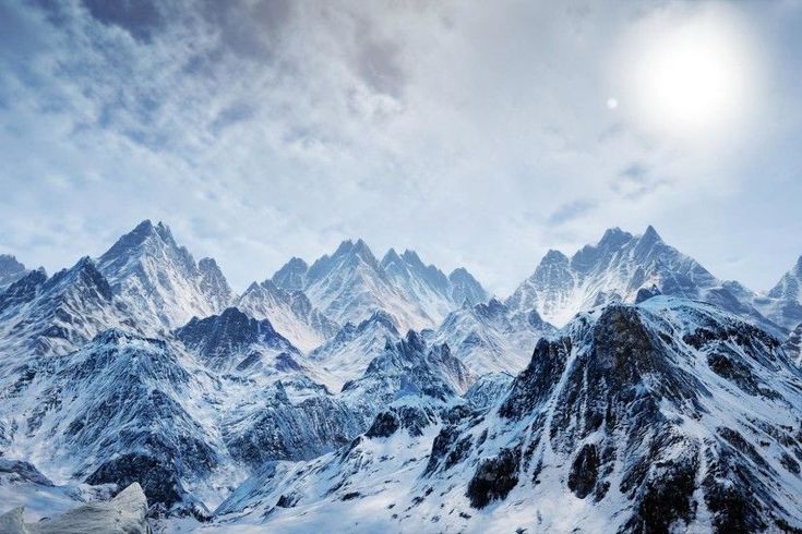 the mountains are covered in snow under a cloudy sky