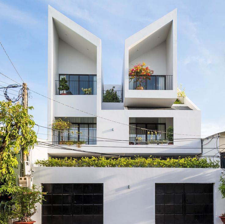 two white buildings with black garage doors and plants growing on the side of each building