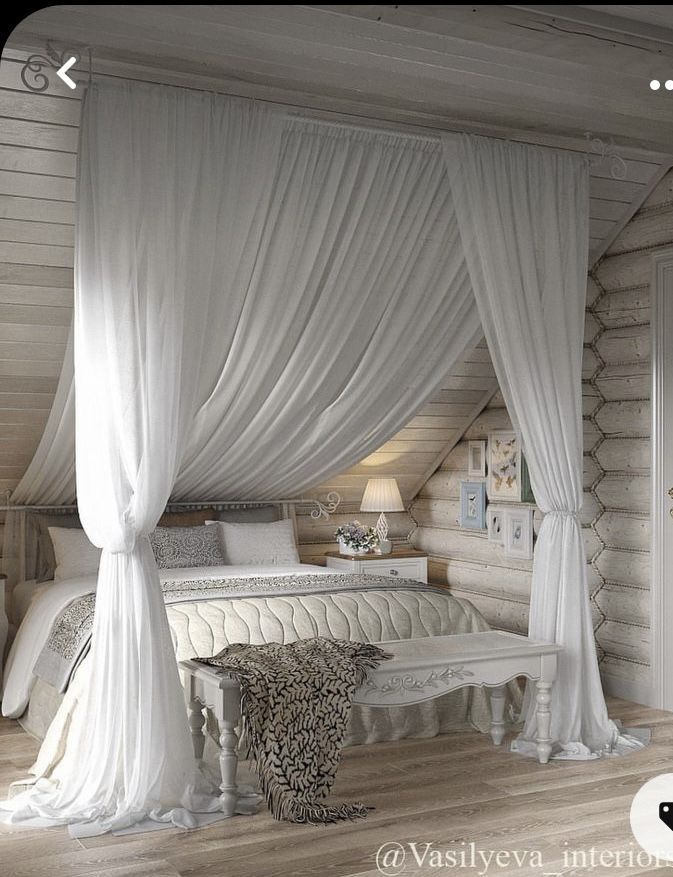 a white bed sitting in a bedroom next to a wooden floor covered in drapes