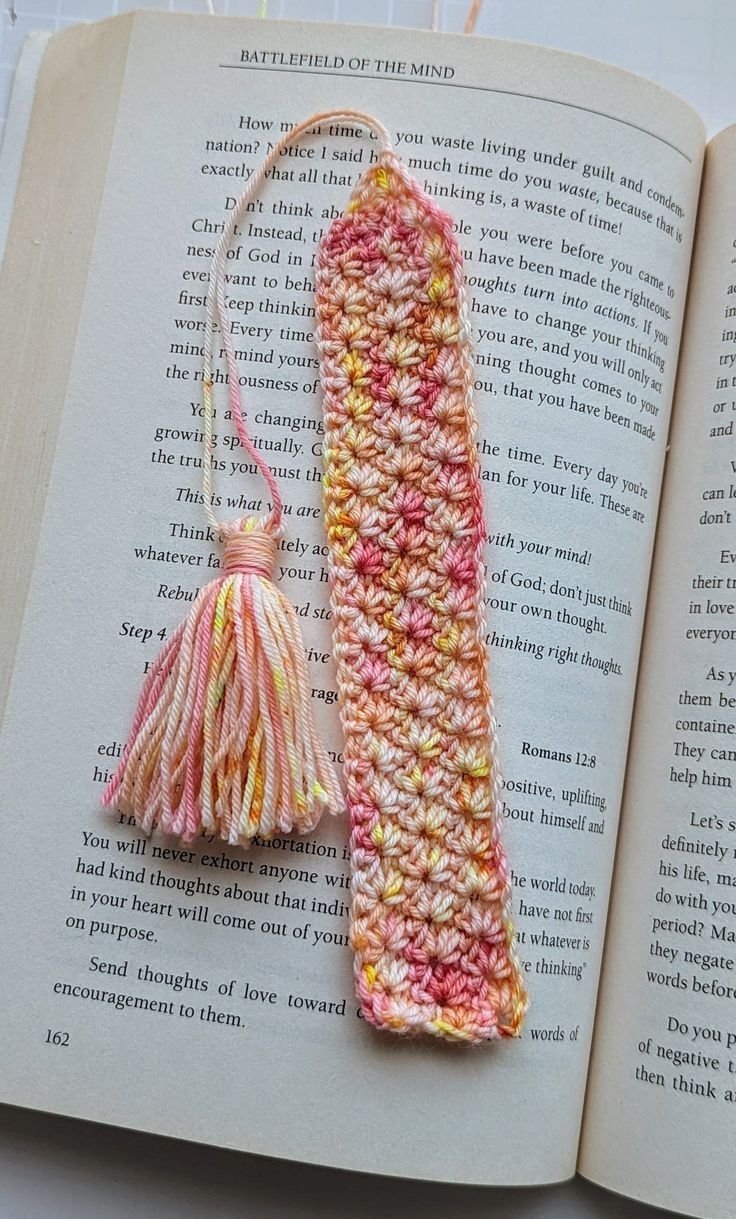 an open book with a crocheted bookmark and tassel