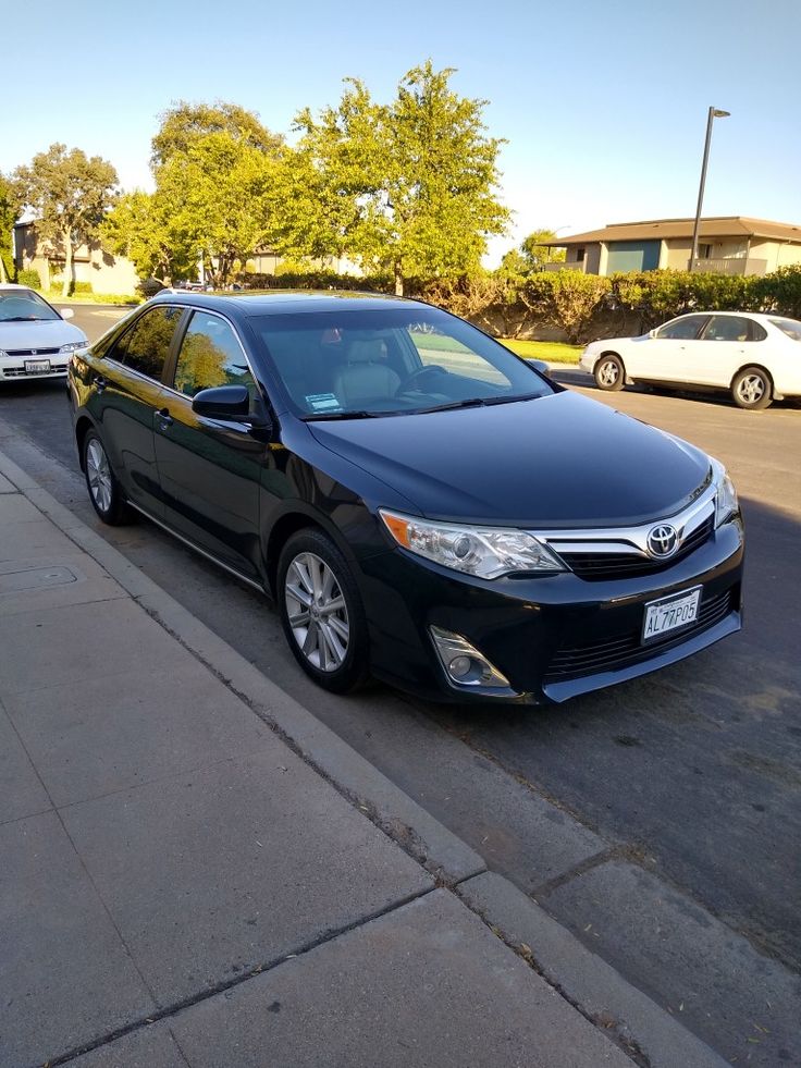 a black car parked on the side of a street next to a sidewalk with cars