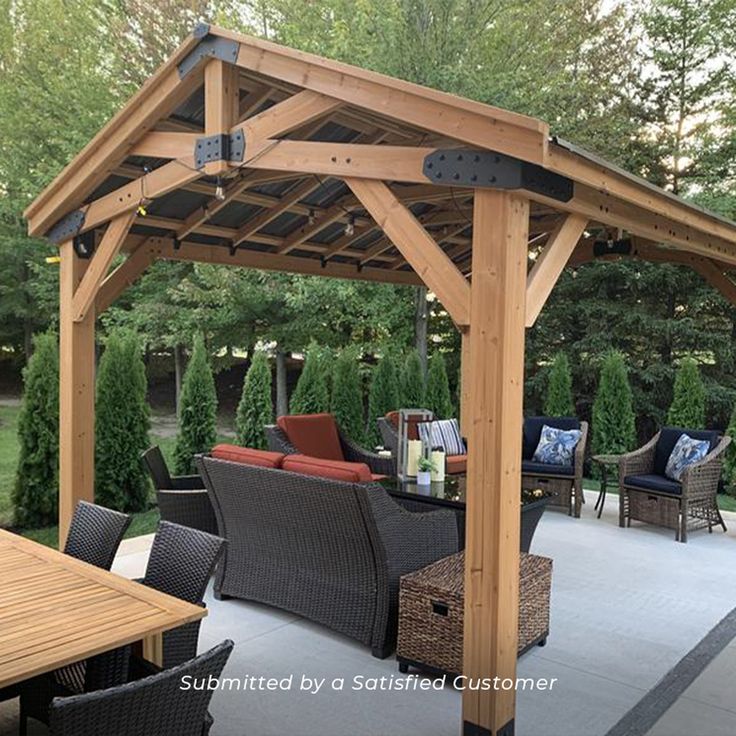 an outdoor covered patio with wicker furniture and wooden pergoline structure, surrounded by greenery