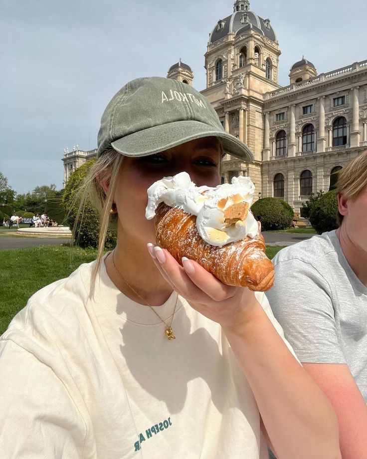 a woman is eating a pastry in front of a large building