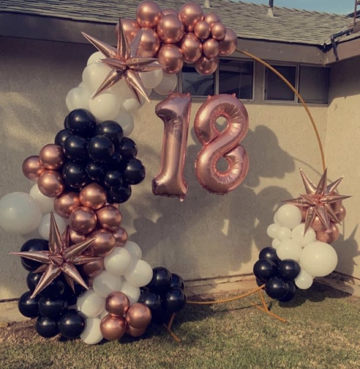 balloons and stars are arranged in the shape of numbers on a house's front lawn