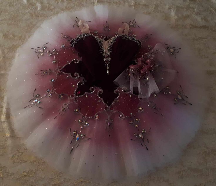 a pink and white tutu with hearts on the top, surrounded by small crystals